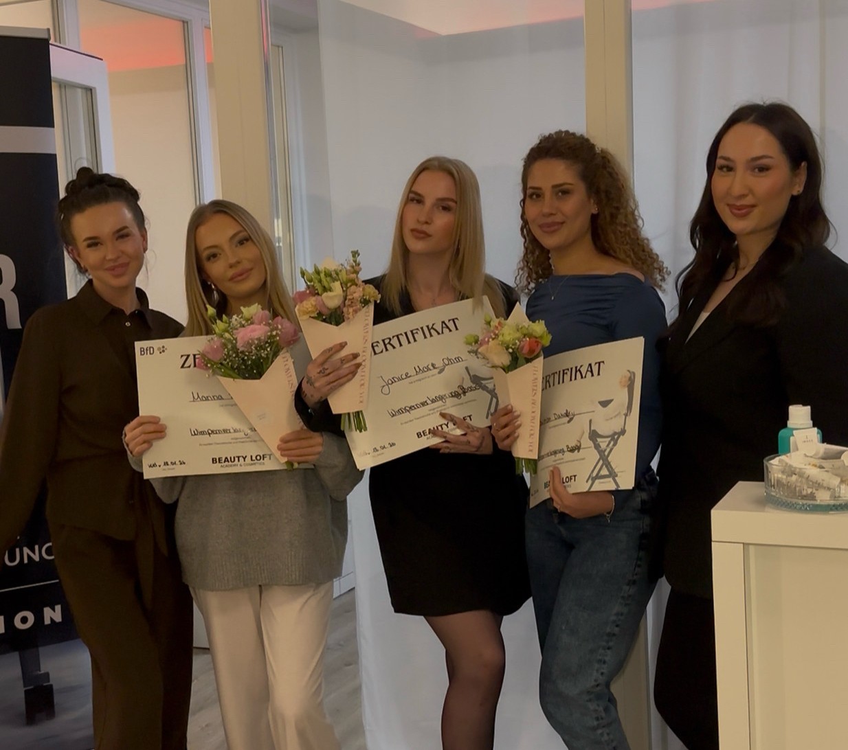 Absolventinnen mit Zertifikaten und Blumen